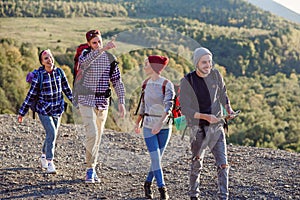 Two hipster couples with backpacks hiking in the mountains during long trip. Happy caucasian group of travelers have an