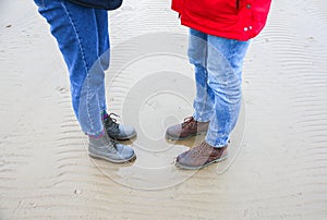 Two hipsters standing on the cold beach. Couple hugging and holding hands. Love story near the ocean. Winter season on the sea.