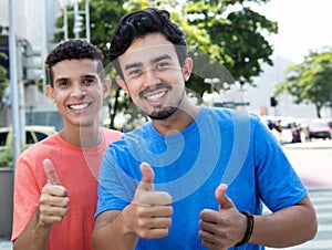 Two hispanic guys showing thumbs in city