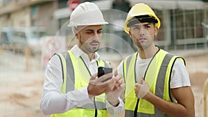 Two hispanic men architects using smartphone speaking at street