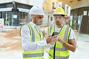 Two hispanic men architects using smartphone standing at street