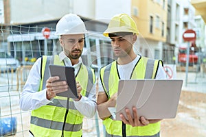 Two hispanic men architects using touchpad and laptop working at street