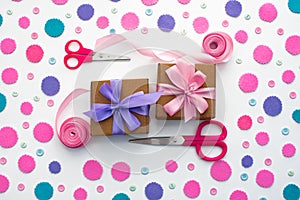 Two holiday gift boxes are tied with satin ribbon on background with colorful confetti.