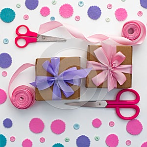 Two holiday gift boxes are tied with satin ribbon on background with colorful confetti.