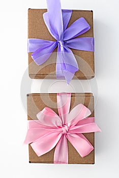 Two holiday gift boxes tied with satin ribbon on white background.