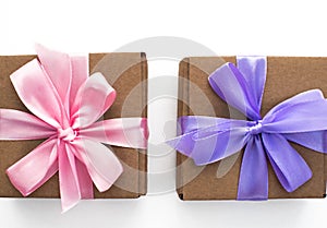 Two holiday gift boxes tied with satin ribbon on white background.