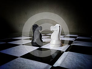 Two horse of opposite team in front of each other while chess battle on chess board