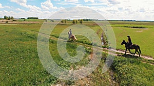 Two Horse Riders On A Flaxen And A Seal Brown Horse Moving Across The Farm Field