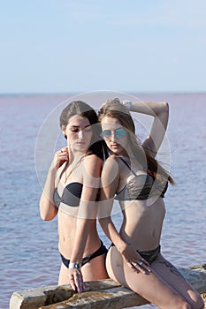 Two hot sexy brunettes  posing near the lake