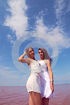 Two hot sexy brunettes in a white dresses posing near the lake