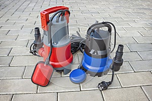 Two household submersible pump with plastic housings  on stone floor