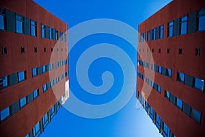 Two houses in front of each other. Photo take from low angle; two red suburban buildings facing eachother with blue sky in backgro