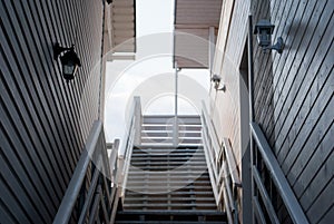 Two houses stand side by side, balconies, stairs, roofs, against the blue sky