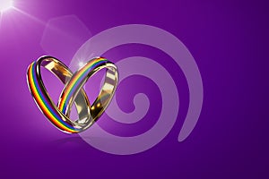 Two hovering wedding rings with rainbow colors isolated on purple background. Equal rights movement for gay marriages and gender