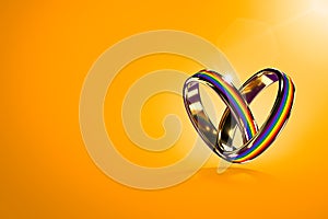 Two hovering wedding rings with rainbow colors  on orange background. Equal rights movement for gay marriages and gender photo