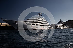 Two huge yacht in port of Monaco at sunset, glossy board of the motor boat, the chrome plated handrail, megayacht is photo