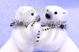 Two hugging white polar bears toys christmas decorations in necklaces from tinsel with pine cones on a snow background