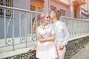 Two hugging girls near the fence in the city