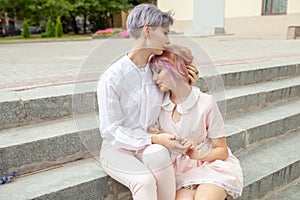 Two hugging girls sitting on the stairs in the city