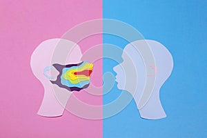 Two human profiles cut out of paper and profile on the left is in a rainbow mask