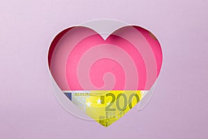 The two hundred euro banknote is in a pink heart on a purple background. Minimal concept money, love