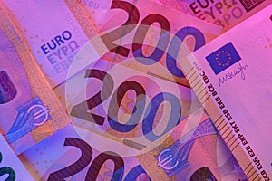 Two hundred euro bills close-up in purple neon light. Money colored background.Inflation of money in the EU countries