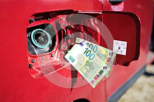 Two hundred-euro bills in front of the fuel tank of a car