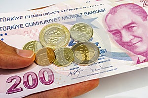 Two hundred turkish liras and turkish coins in hand.