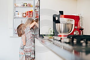 Two hungry female children irresistibly hungry searching for food in the fridge photo
