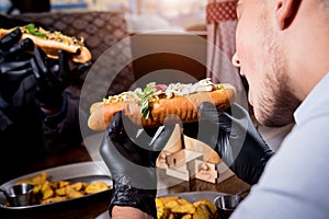 Two hungry young men eating a hot dogs in cafe. Restaurant