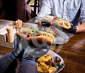 Two hungry young men eating a hot dogs in cafe. Restaurant