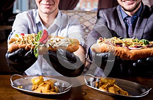 Two hungry young men eating a hot dogs in cafe. Restaurant