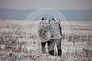 Two hunters in winter camouflage to sneak up on the field