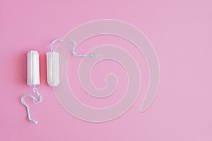 Two hygienic tampons on a pink background.