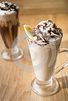 Two Iced coffee milkshake on a woodon table with a wood background