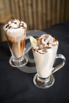 Two Iced coffee milkshake on a woodon table with a wood background