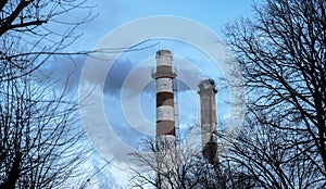 Two idustrial pipes with smoke on blue sky background. Air industrial pollution