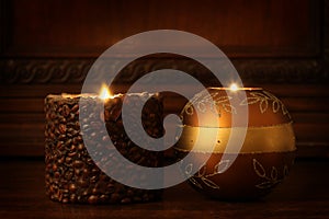 Two ignited candles rest on a wooden shelf with copy space for your text