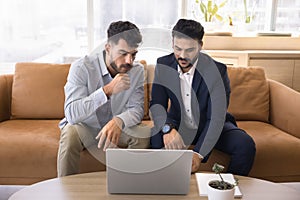 Two Indian and Arab business men watching online content