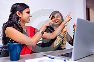 Two indian colleages discussing ideas using a tablet computer at the office