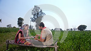 Two Indian farmers / workers eating food / lunch together after working hard the whole day