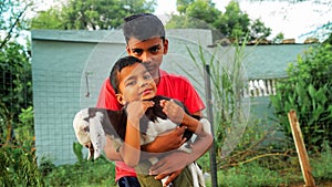 Cute children holding a goat lings in a farmland. Little kids caring for the goatling on the farm. farmland. Village life