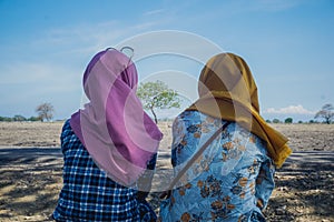 Two Indonesian girls in hijab are sitting in Baluran Park