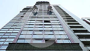 Two industrial climbers are washing, cleaning facade of a modern office building