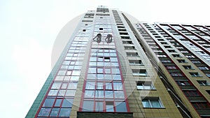 Two industrial climbers are washing, cleaning facade of a modern office building