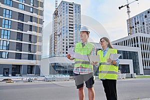 Two industrial construction workers discussing project plan for engineering work