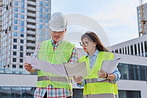 Two industrial construction workers discussing project plan for engineering work
