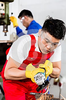 Two industrial workers in Asian metal factory