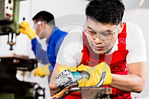 Two industrial workers in Asian metal factory