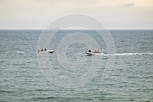 Two inflatable boats sail towards each other in the sea